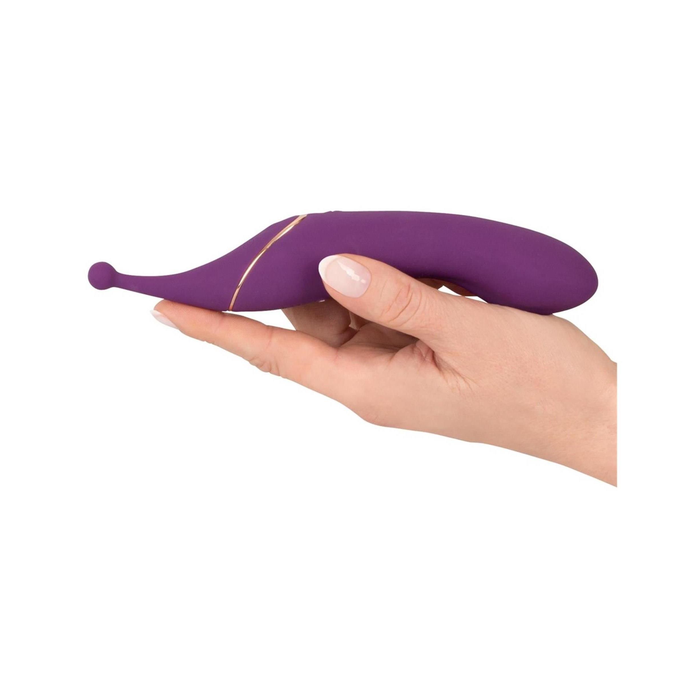 Lila Vibrator in einer Hand gehalten. Goldfarbene Akzente. Tropfenförmig, abgerundete Spitze. Glatte Oberfläche.