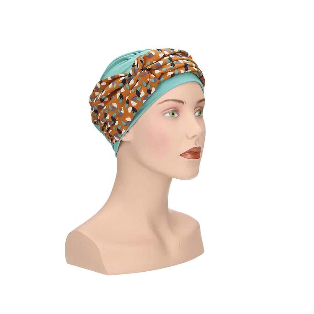 Türkisfarbener Turban mit gemustertem Stirnband auf einer Schaufensterpuppe. Das Stirnband hat ein Muster aus Braun-, Blau- und Beigetönen. Seitenansicht.