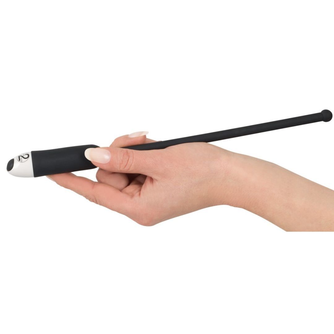 Schwarzer Dilator in einer Hand gehalten. Spitze mit weißem Element und Zahl 2.  Lange, schlanke Form.
