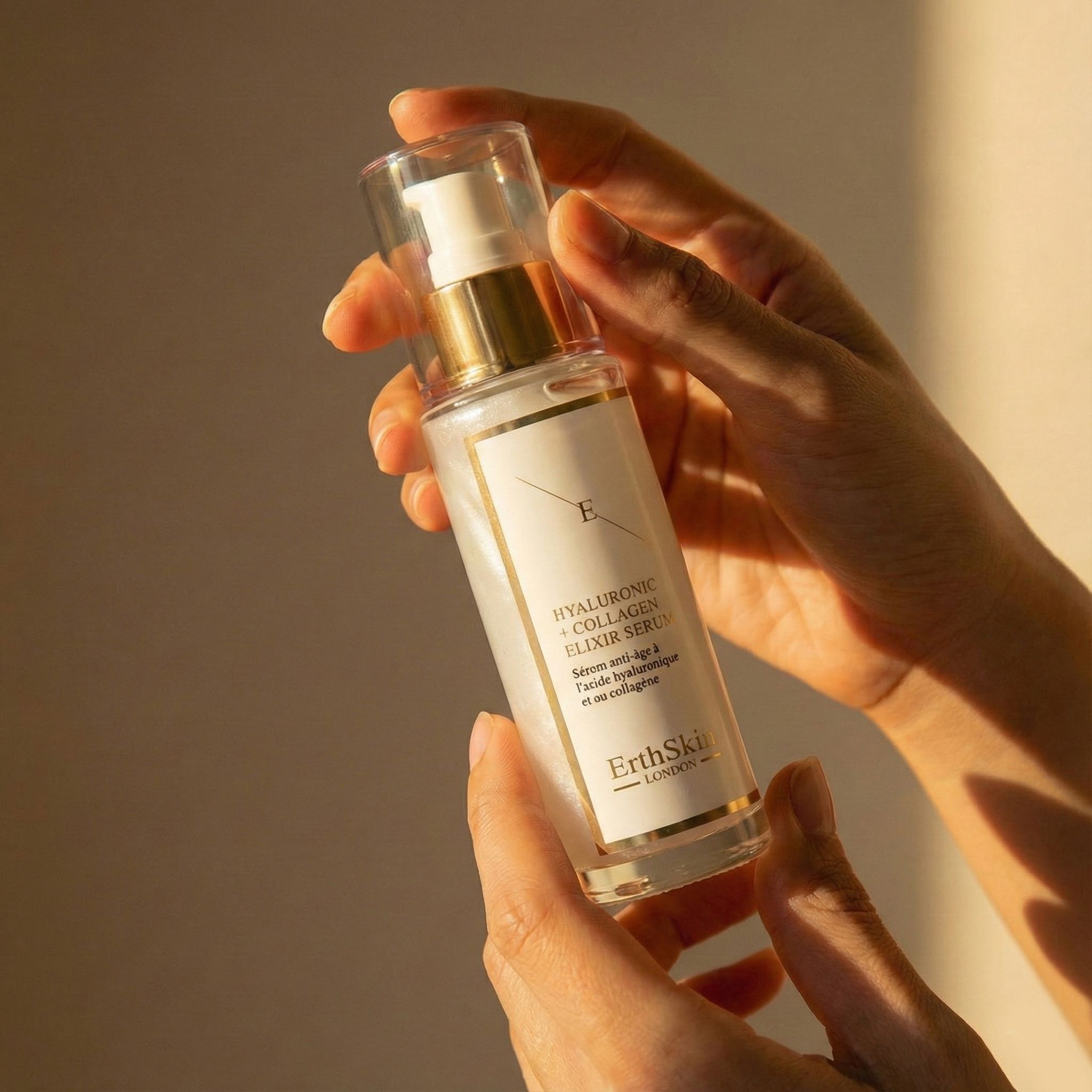 Hände halten eine Flasche ErthSkin London Hyaluronsäure & Kollagen Elixir Serum.