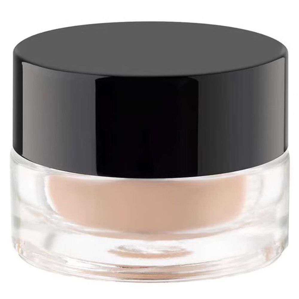 Runder Tiegel mit schwarzem Deckel. Der Tiegel ist aus transparentem Glas. Inhalt: beigefarbene Creme.