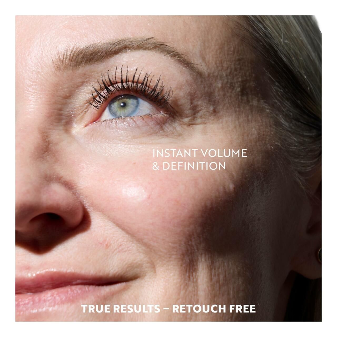 Nahaufnahme eines Gesichts mit getuschten Wimpern. Text: INSTANT VOLUME & DEFINITION, TRUE RESULTS - RETOUCH FREE.