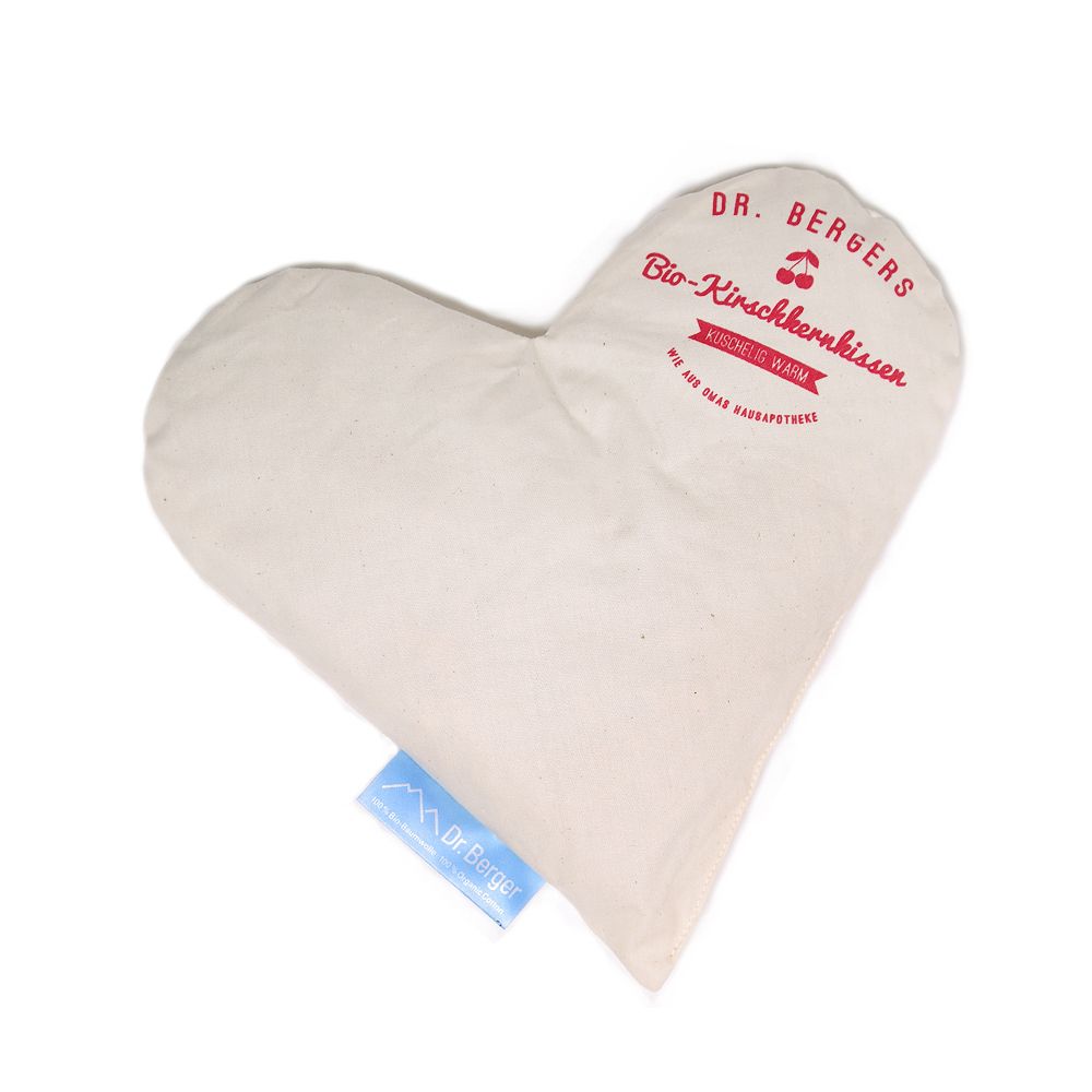 Herzförmiges Kirschkernkissen. Beige Stoff, roter Aufdruck: Dr. Bergers Bio-Kirschkernkissen. Blaues Etikett: Dr. Berger.