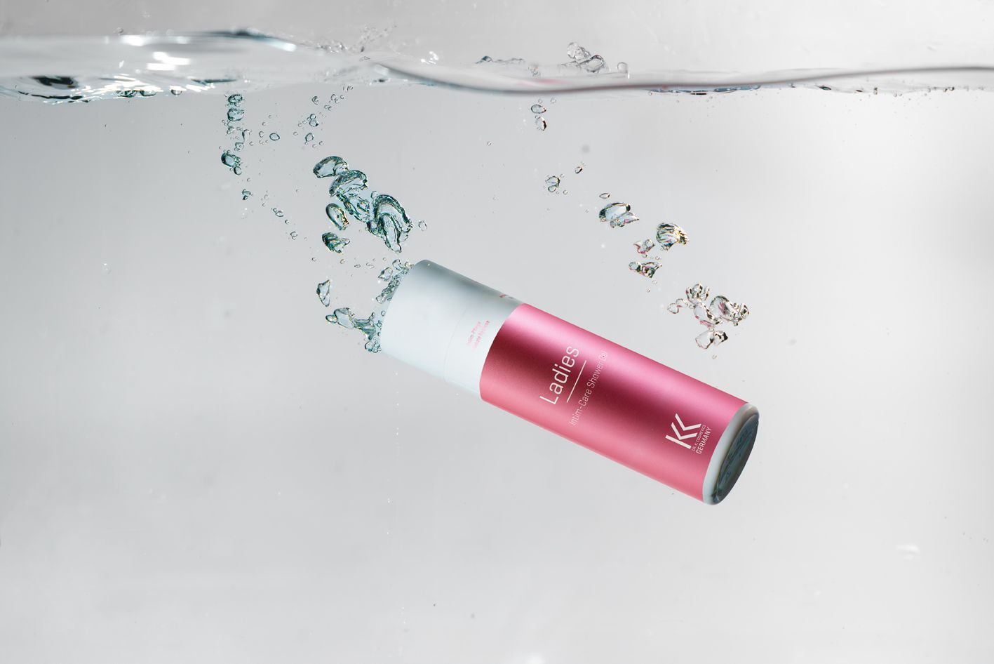 Rosa Flasche im Wasser. Aufschrift "Ladies Intim-Care Shower Gel" und Logo K.K. Cosmetics Germany.