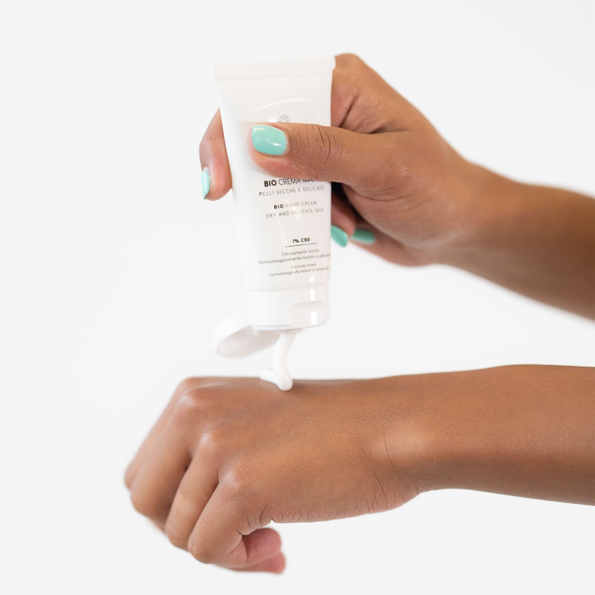 Weiße Tube wird in der Hand gehalten. Produkt wird auf die Hand aufgetragen. Text: BIO CREMA MANI, 1% CBD. Marke: PLANTADEA.