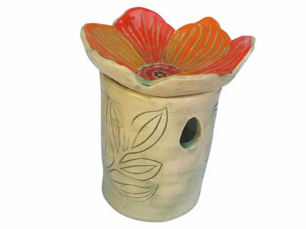 Duftlampe mit orangefarbener Blütenform. Zylindrischer Körper mit Blattmuster. Loch für Teelicht.