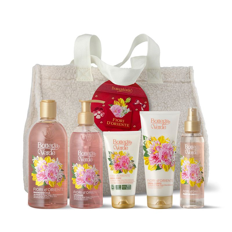 Un maxi sacco Bottega Verde con prodotti Fiori d'Oriente. Include gel doccia, sapone liquido, crema corpo e spray corpo. Tutti i prodotti sono confezionati in tubi e flaconi bianchi con tappi dorati e disegni floreali. Un'etichetta rossa con il nome del marchio è attaccata alla borsa.