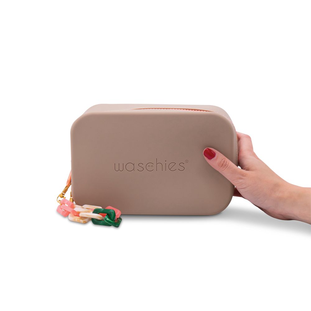 Beige Kosmetiktasche mit Reißverschluss und Anhänger. Eine Hand hält die Tasche.