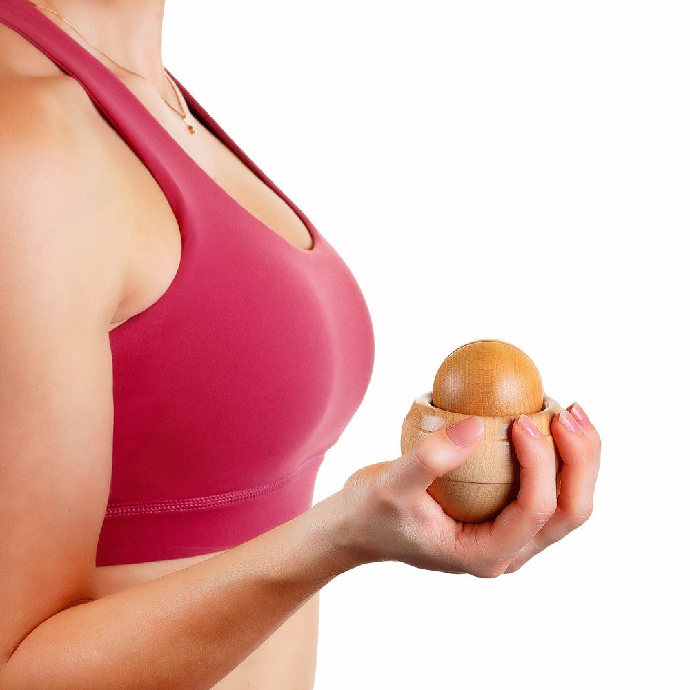 Holz-Massageroller, gehalten von einer Person. Besteht aus einer Kugel und einer Halterung. Natürliches Holz.