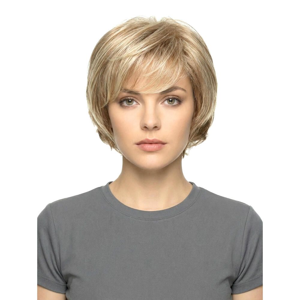 Blonde Perücke mit kurzem, gestuftem Schnitt und Pony. Die Frau trägt ein graues T-Shirt. Frontansicht.