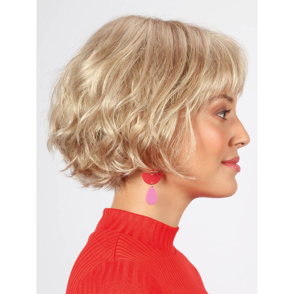 Weißblonde Perücke mit kurzem, gewelltem Schnitt. Frau trägt rotes Oberteil und rosa Ohrringe. Seitenansicht.