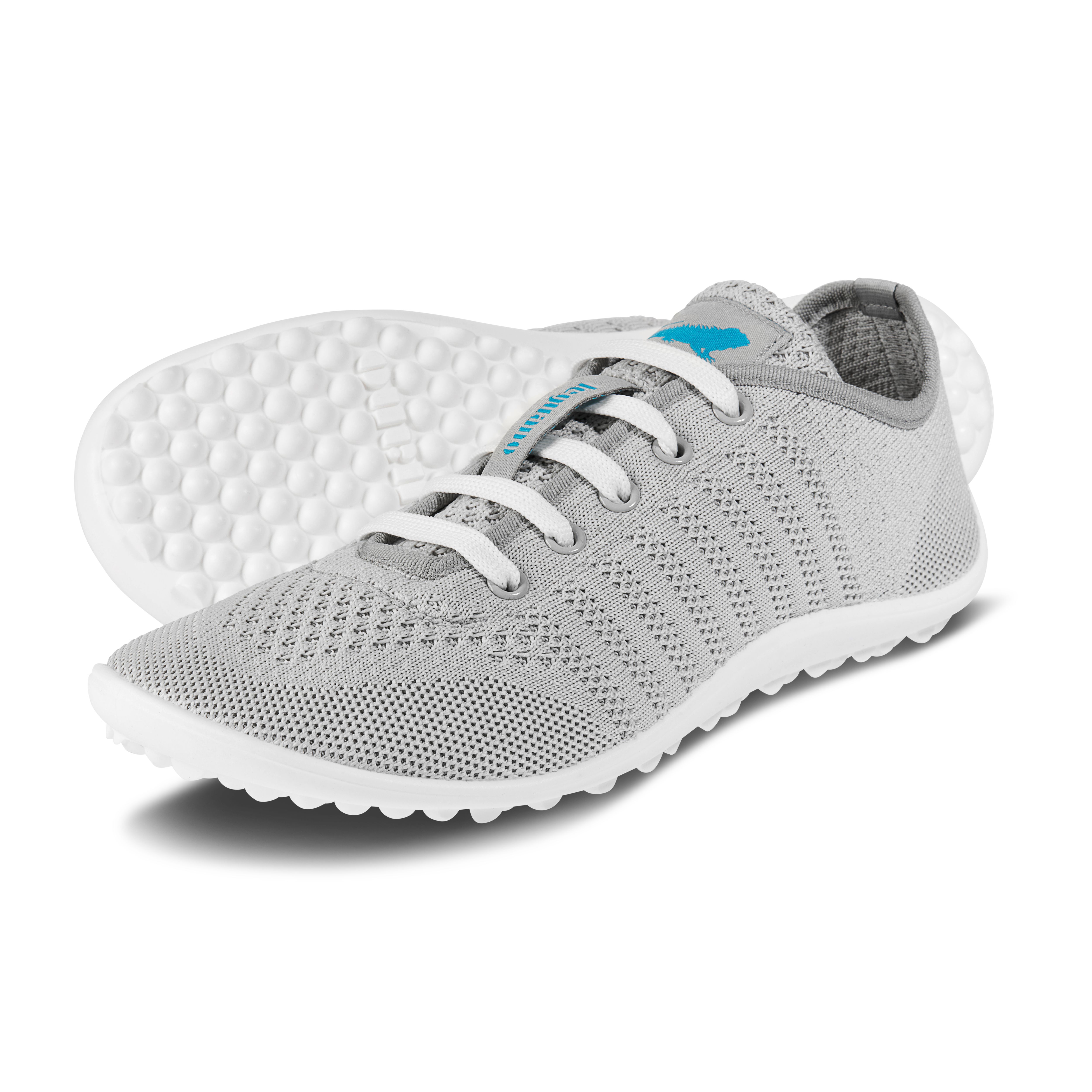 Grauer Barfußschuh mit Schnürsenkeln. Weiße Sohle mit Noppen. Hellgraues, atmungsaktives Obermaterial.