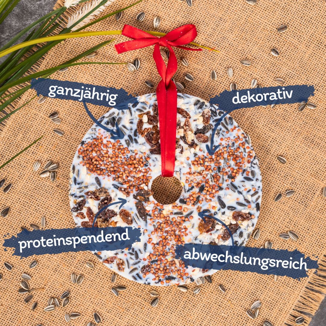 Runder Vogeltaler mit Texten: ganzjährig, dekorativ, proteinspendend, abwechslungsreich. Mit rotem Band.
