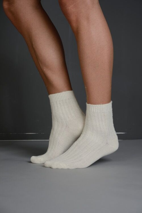Beige Socken mit geripptem Muster. Füße auf grauem Untergrund.