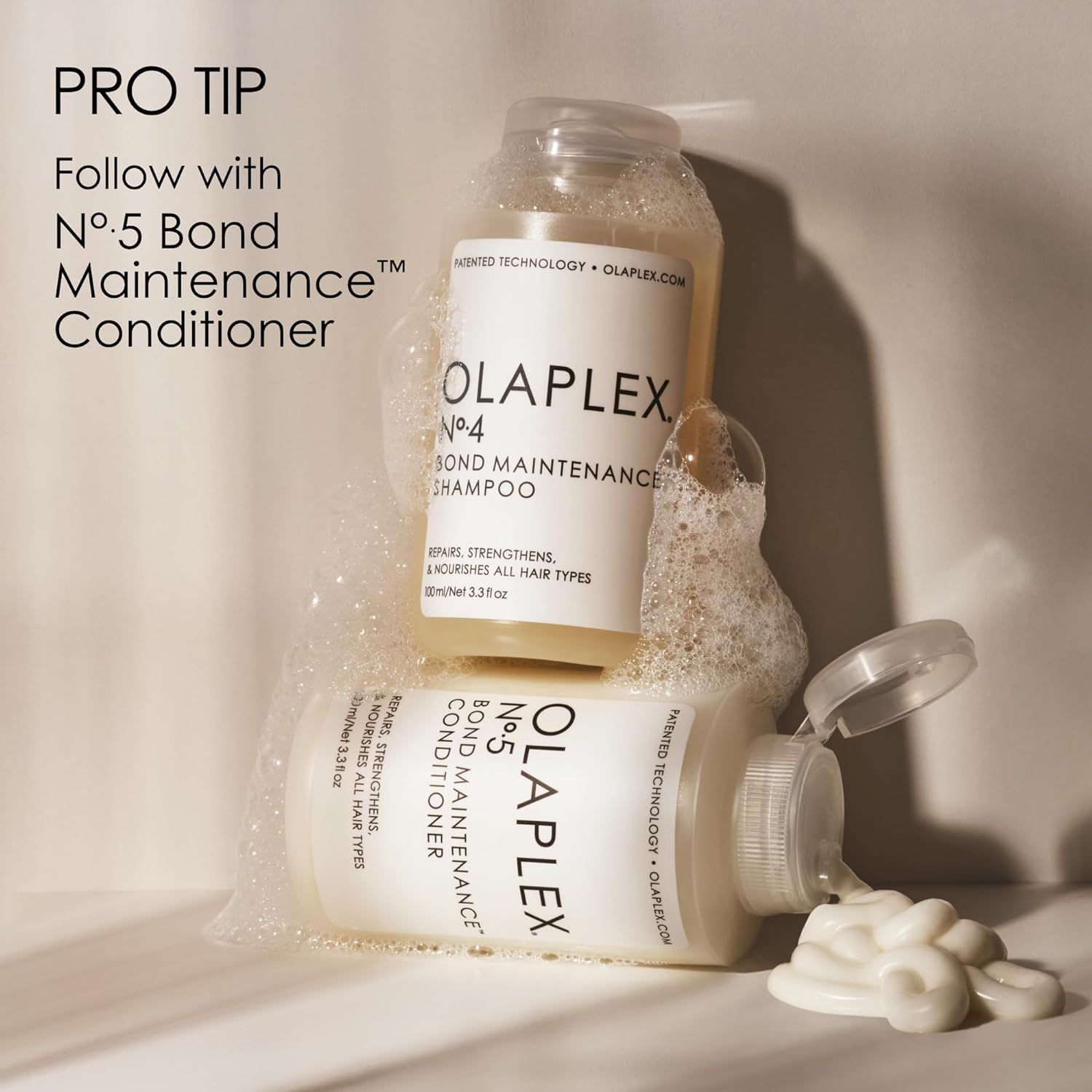 Zwei Flaschen: OLAPLEX No. 4 Shampoo und No. 5 Conditioner. Schaum und Produkt.