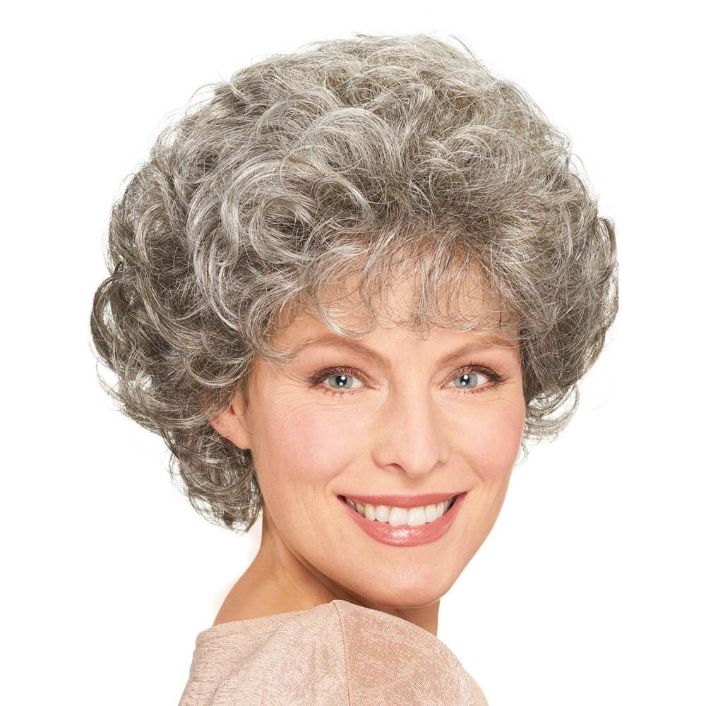 Graumelierte Perücke mit Locken, frontal. Die Frau trägt ein helles Oberteil. Weißer Hintergrund.