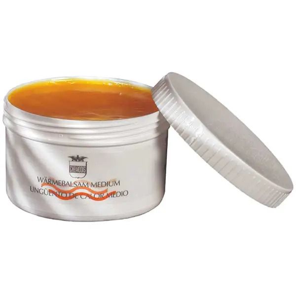 Weißer Tiegel mit orangefarbenem Balsam. Deckel daneben. Schriftzug: Wärmebalsam Medium.
