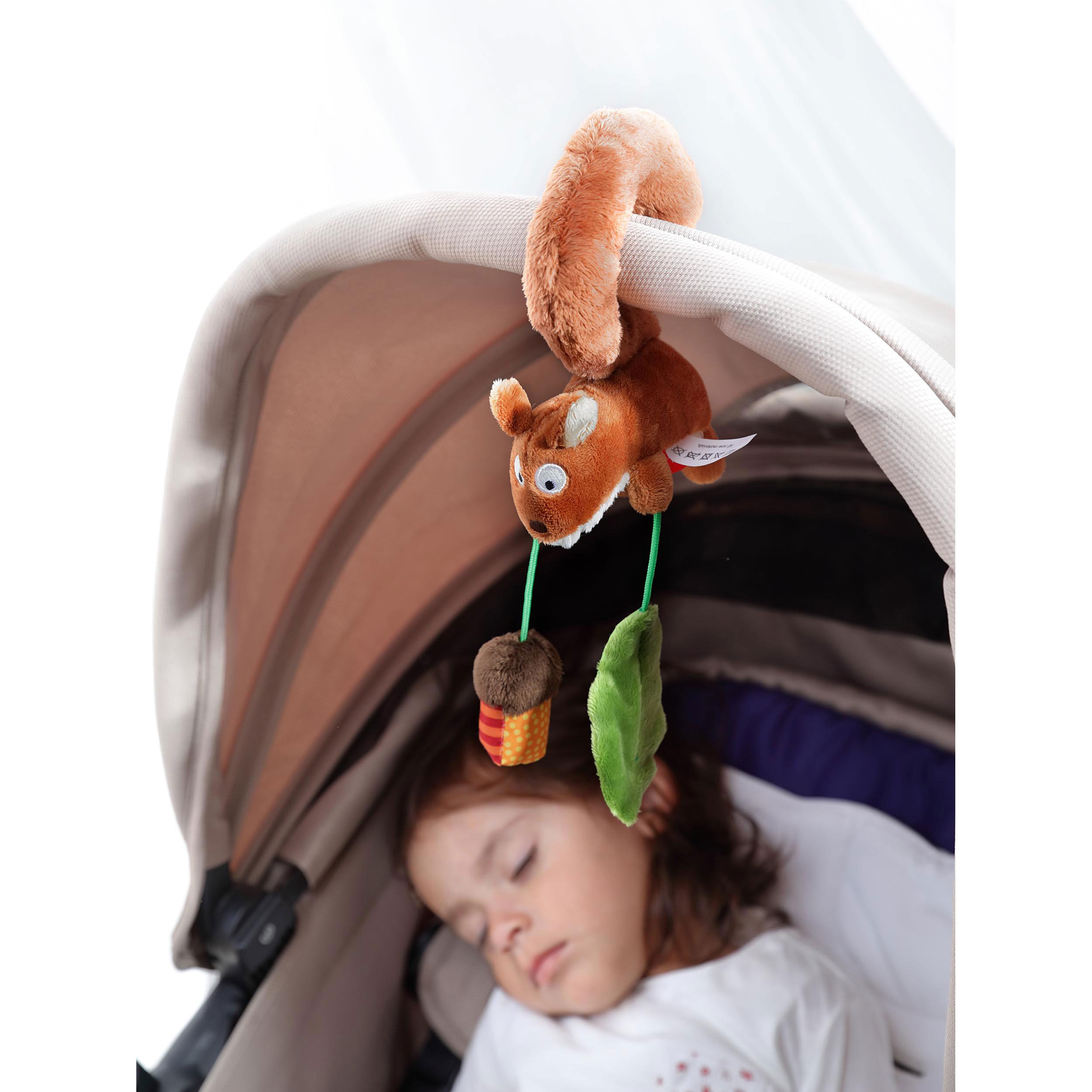 Plüsch-Eichhörnchen-Anhänger an Kinderwagenhaube, neben schlafendem Baby.