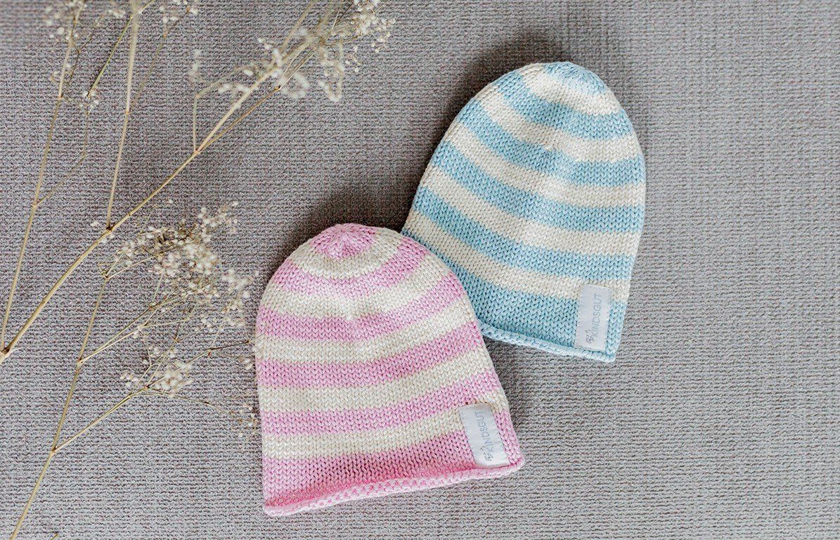 Zwei gestreifte Kindermützen. Rosa-weiß und blau-weiß. Label mit Kindsgut-Logo.