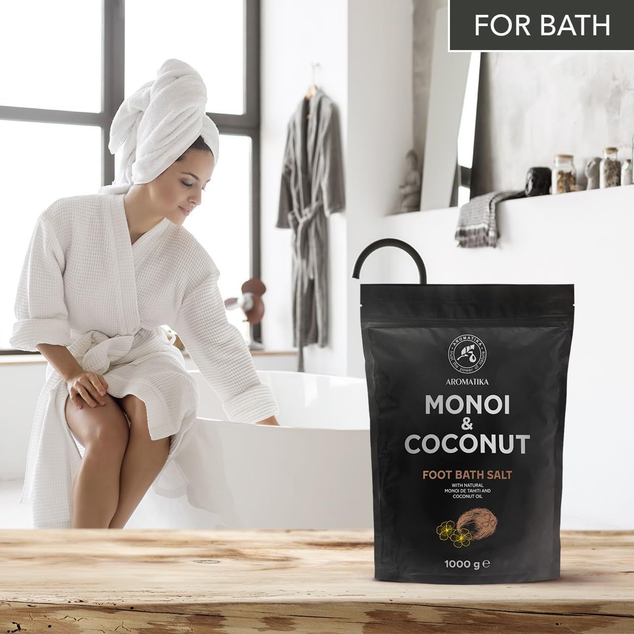 Produktverpackung neben einer Frau im Bademantel. Text: Monoi & Coconut Foot Bath Salt. Im Hintergrund ein Bad.