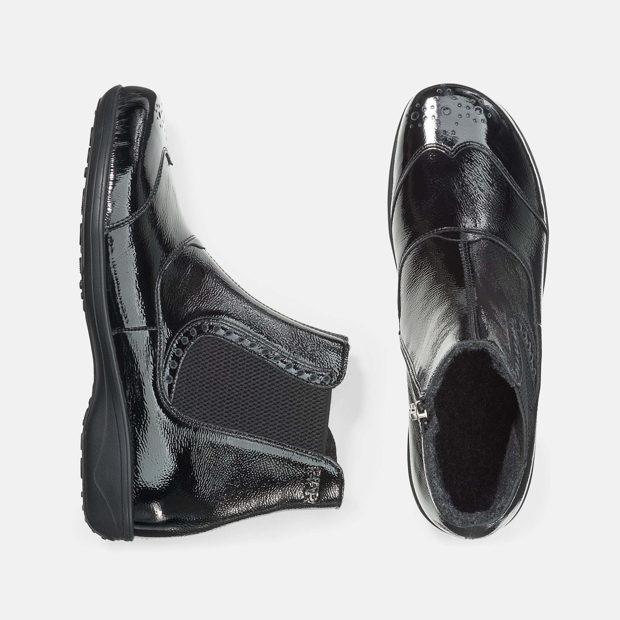 Draufsicht auf zwei schwarze Stiefeletten. Glänzendes Obermaterial, Reißverschluss, seitlicher Gummizug.