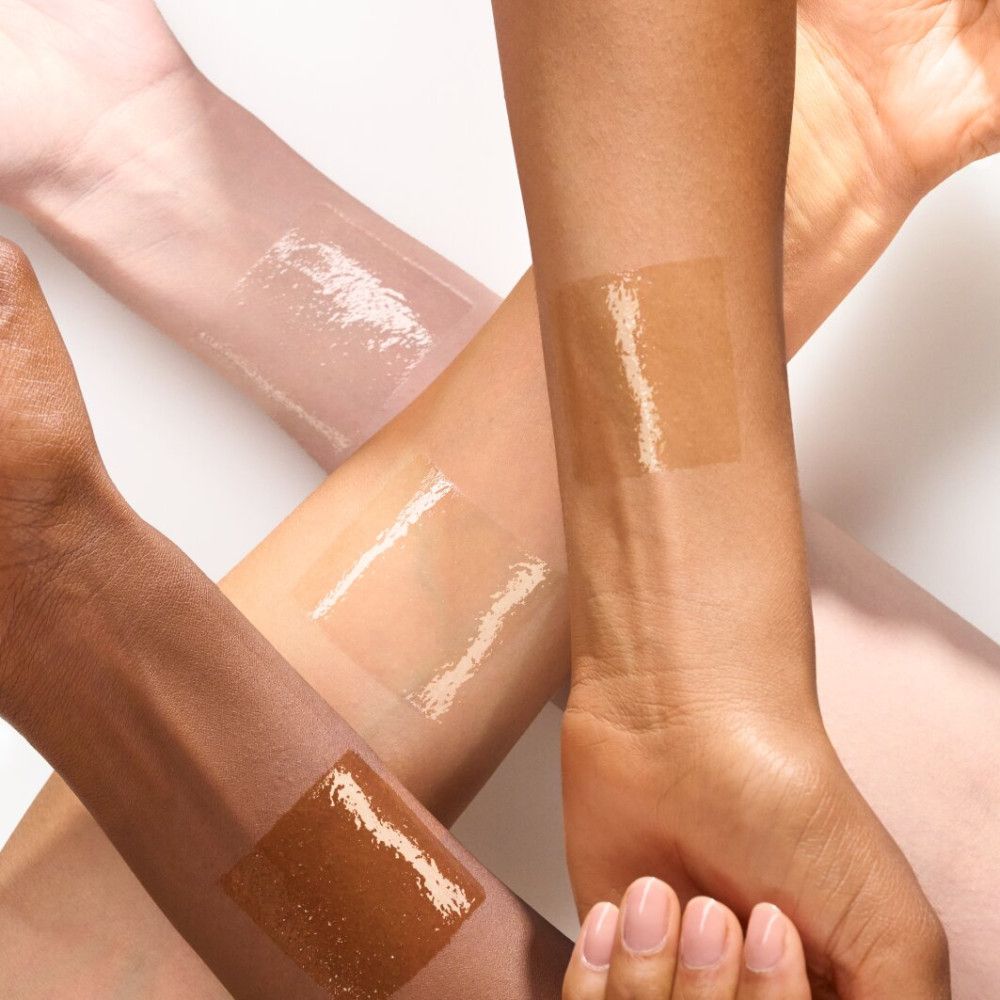 Arme mit Lipgloss-Flecken in verschiedenen Hauttönen. Der Lipgloss ist transparent und glänzend.