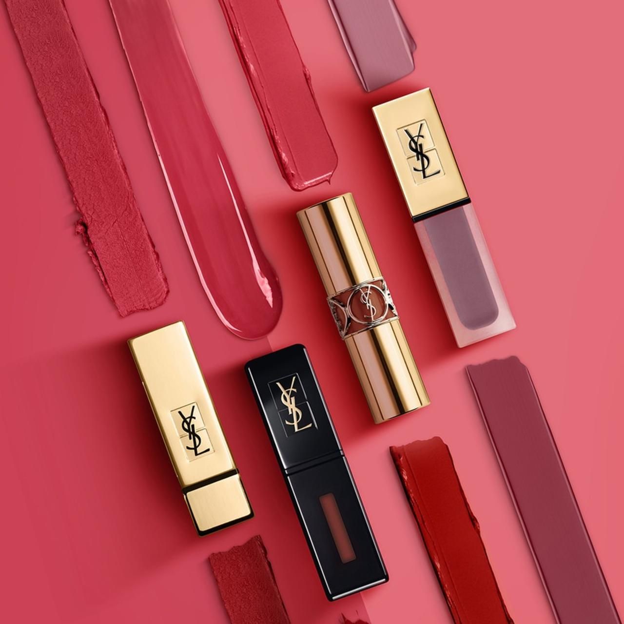 Verschiedene Lippenstifte und Lippenstiftfarben auf rosa Hintergrund. YSL-Logo auf den Lippenstiften.