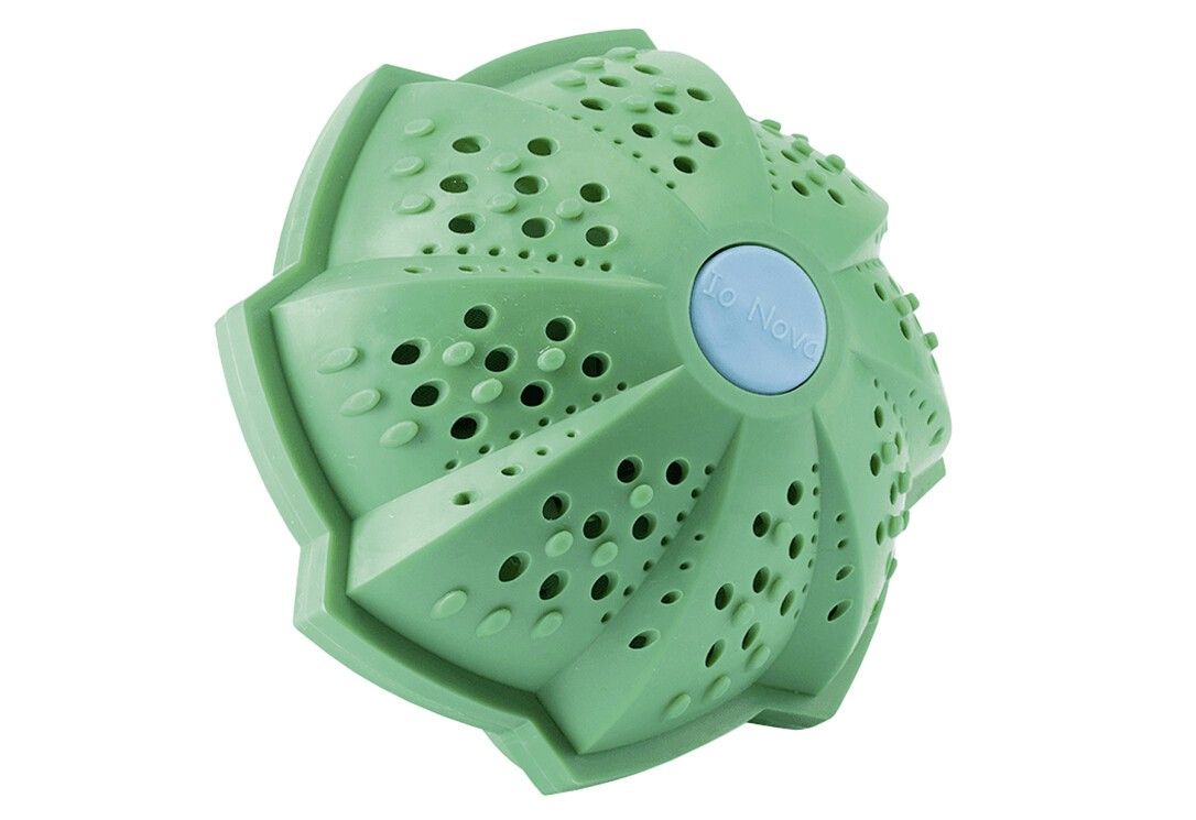 Grüner Waschball mit Löchern und Noppen. Blauer Knopf mit "IO Nova"-Schriftzug. Mehrere Blütenblätter.