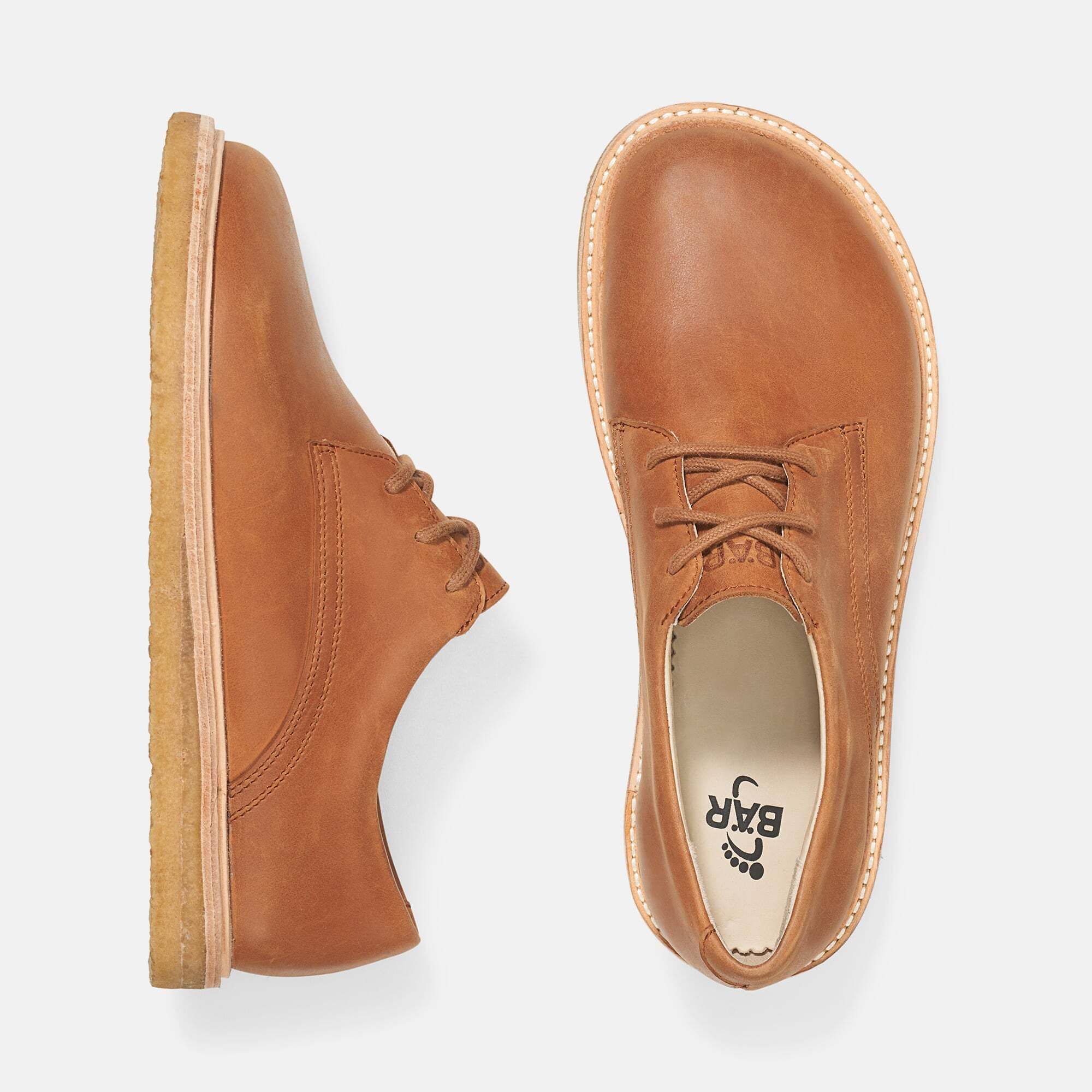 Zwei braune Lederschnürschuhe mit breiter Sohle. Hellbraune Schnürsenkel. Hellbraune Sohle. Blick von oben.