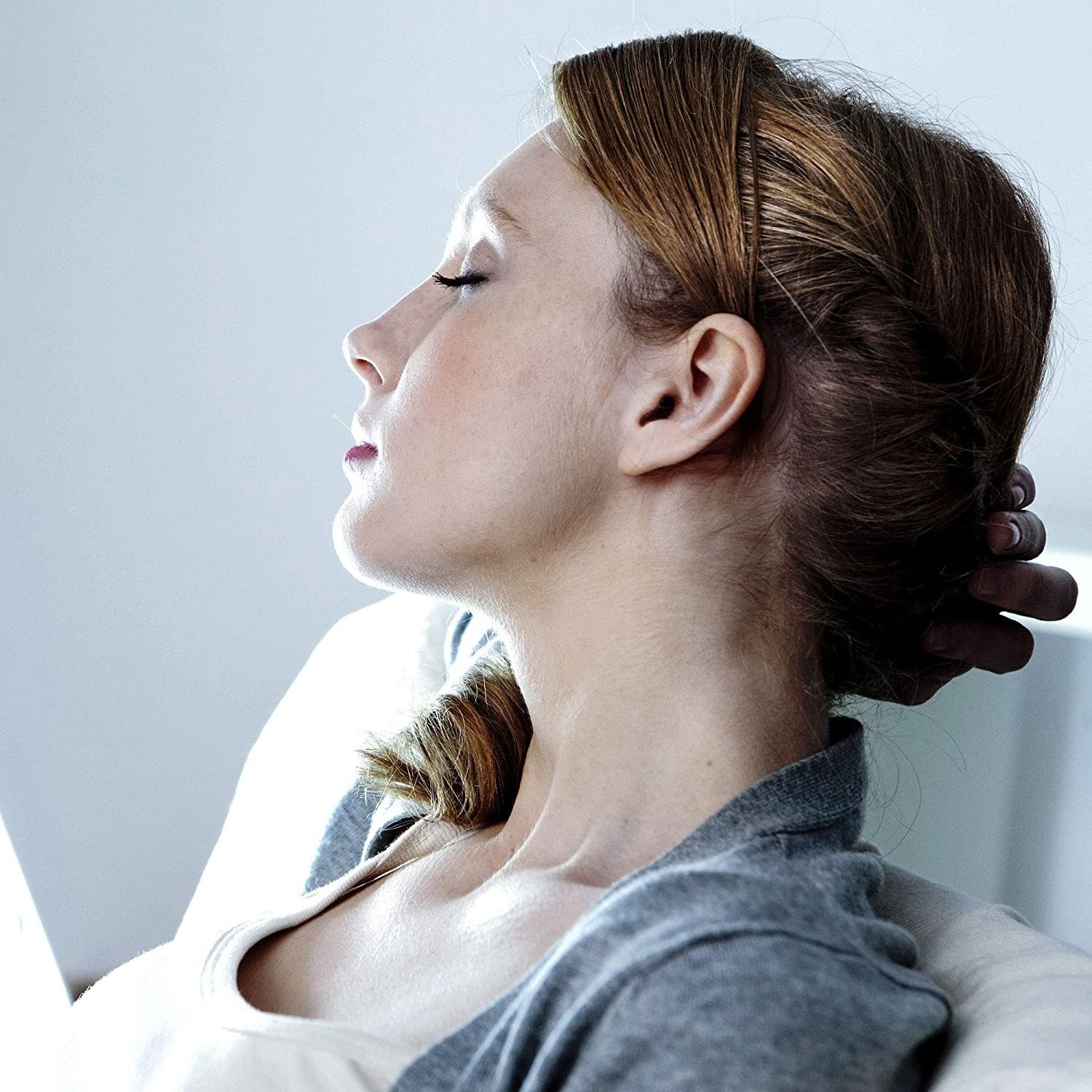 Femme avec lampe de luminothérapie. Elle tient sa main sur sa tête. La lampe est en arrière-plan.