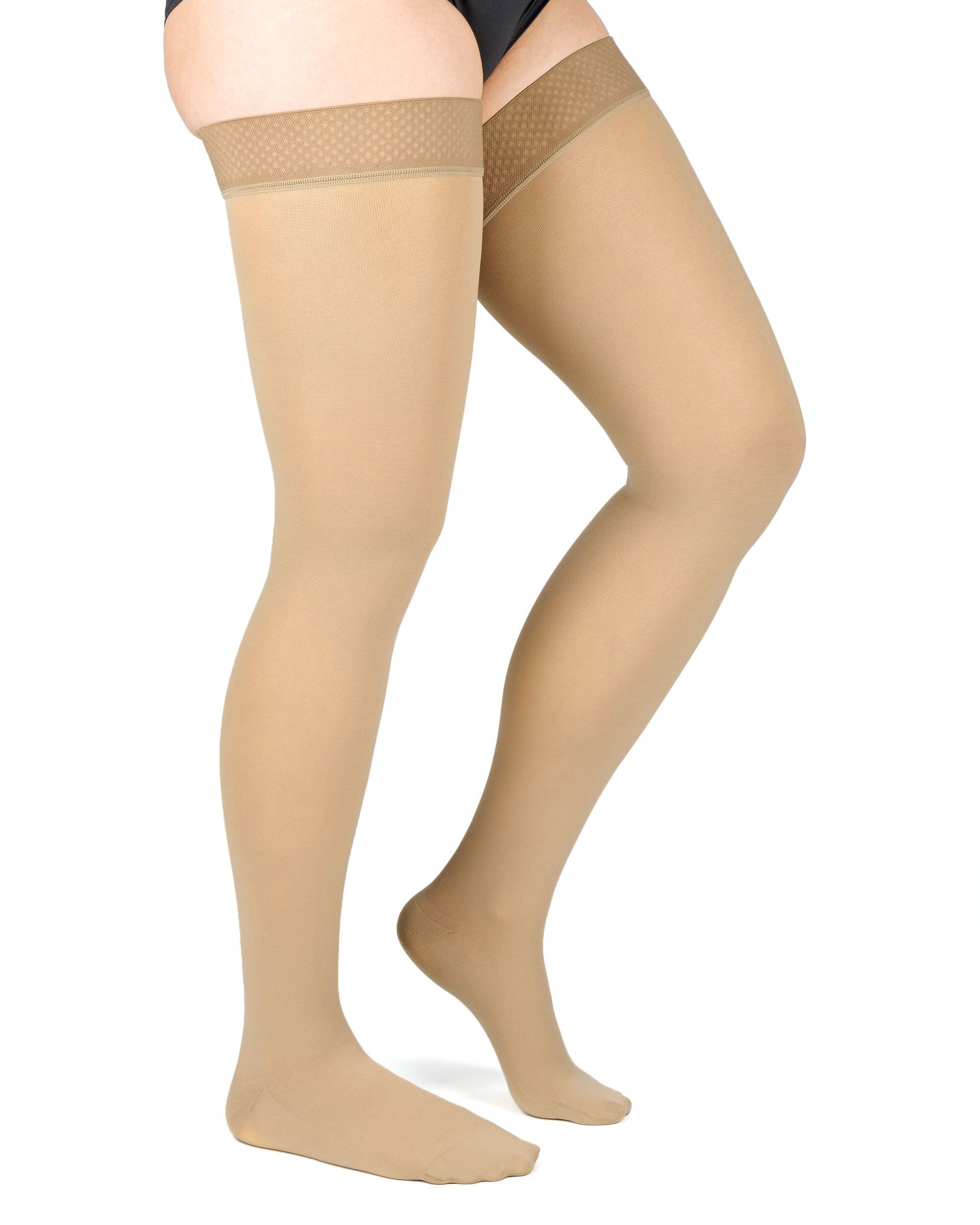Hautfarbene Kompressions-Schenkelstrümpfe. Oben mit einem strukturierten Band. Auf weißem Hintergrund, von der Seite.