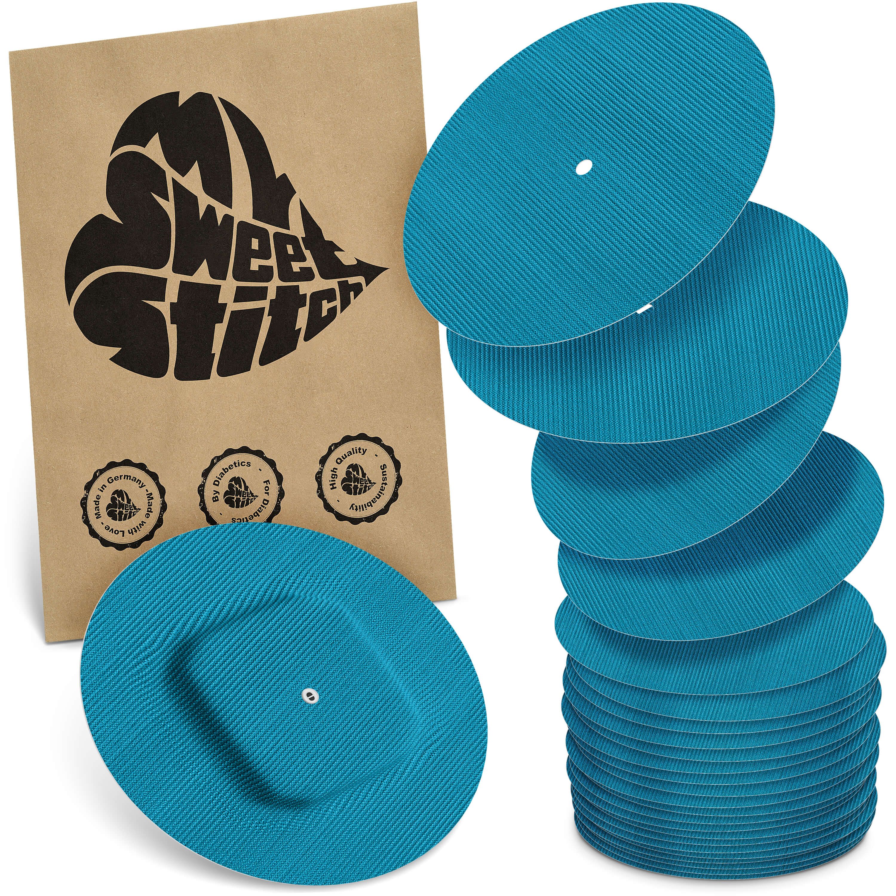 Türkisfarbene, runde Pflaster mit geriffelter Oberfläche. Einige haben eine quadratische Aussparung. Braune Verpackung mit Logo.