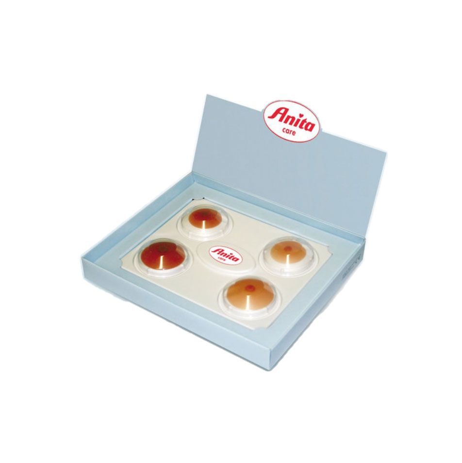 Hellblaue Schachtel mit fünf runden, farbigen Produkten. Anita-Logo oben und auf einem Produkt. Transparente Verpackung.