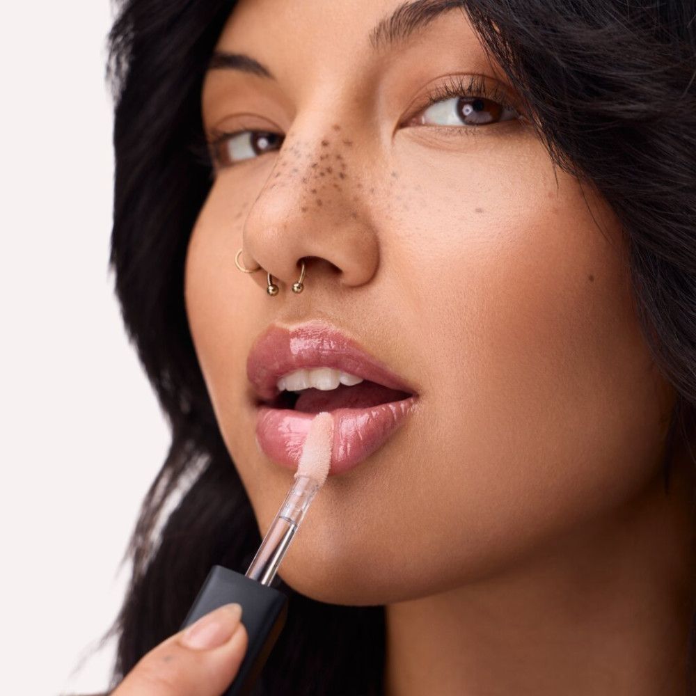 Person trägt Lipgloss auf. Applikator mit Schwammspitze. Produktname nicht sichtbar. Nahaufnahme.