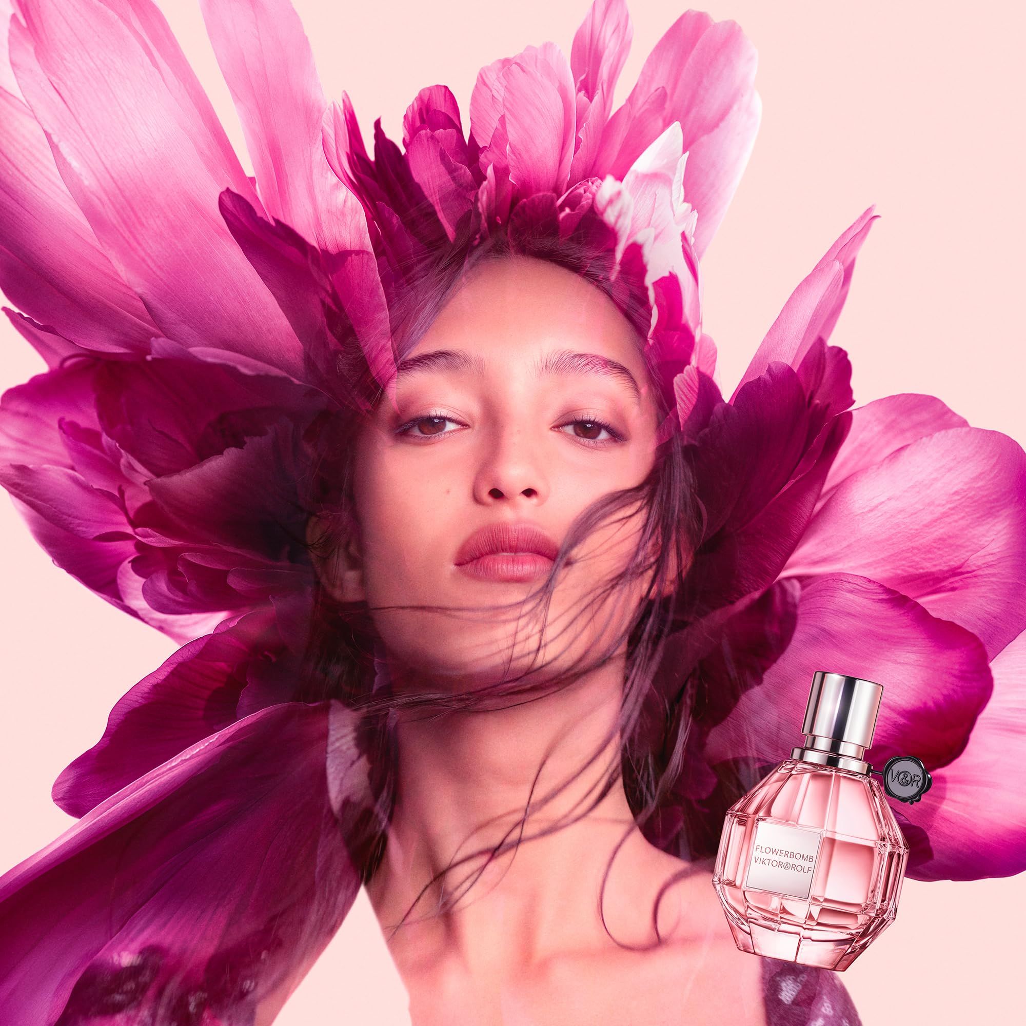 Frau mit Blumen-Kopfschmuck und Flowerbomb-Parfümflakon von Viktor & Rolf. Rosa Hintergrund. Flakon in der rechten unteren Ecke.