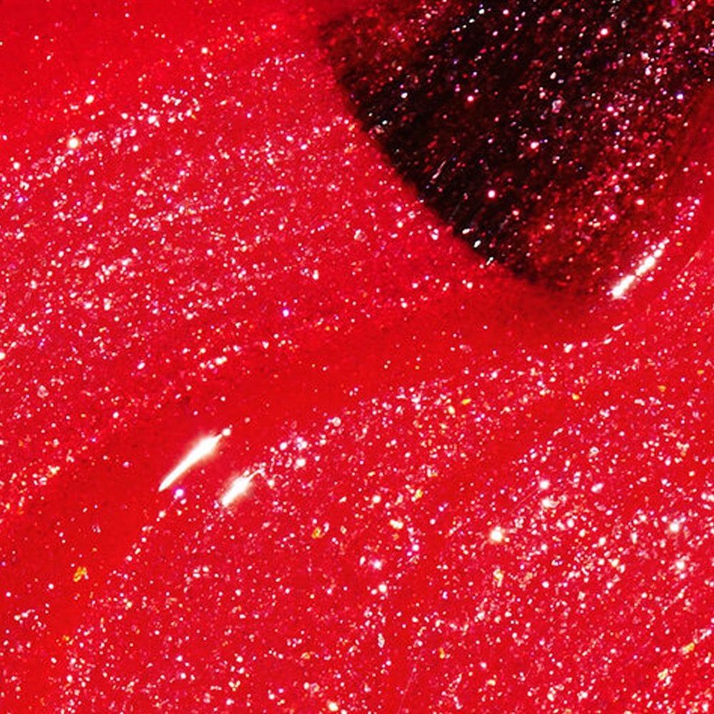 Nahaufnahme von rotem Nagellack mit Glitzer. Der Pinsel ist teilweise sichtbar. Die Textur ist glänzend.