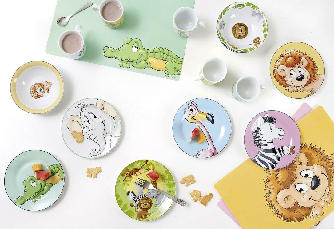Happy Zoo Geschirr-Set mit Tellern, Bechern und Schüsseln. Verschiedene Tiermotive. Kekse und Dekoration auf dem Tisch.