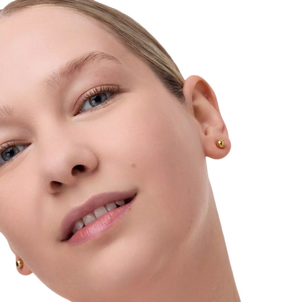 Nahaufnahme eines Gesichts. Frau mit blonden Haaren, blauen Augen und goldenen Ohrringen. Blick nach oben.