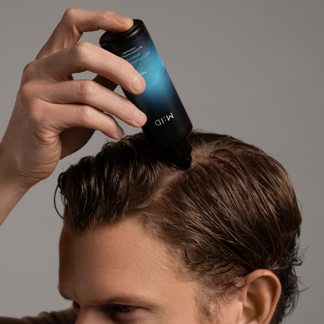 Person trägt das Produkt auf die Kopfhaut auf. Aufschrift: M:ID, Tonic, Anti-Haarausfall Sensitiv.