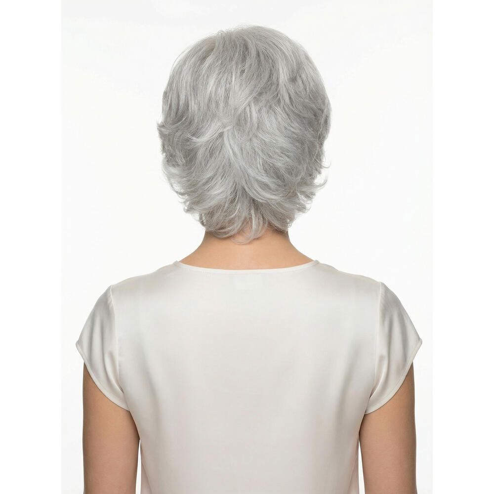 Rückansicht einer Frau mit grauer Perücke. Kurze, gewellte Frisur. Helles Oberteil. Weißer Hintergrund.