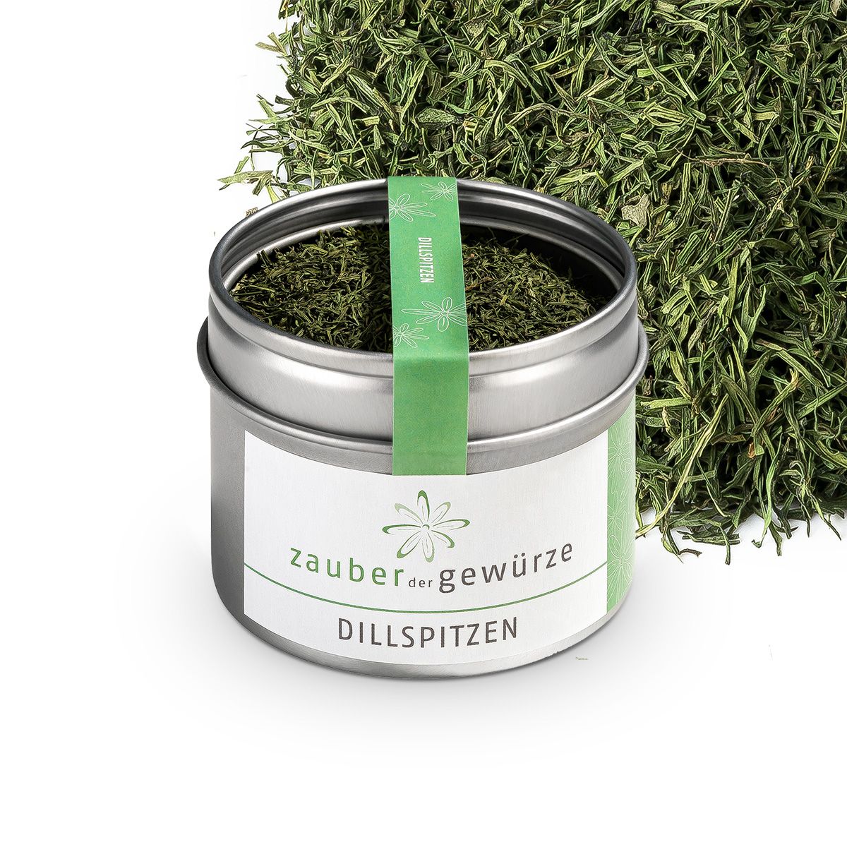 Metallbehälter mit Dillspitzen, daneben lose Dillspitzen. Weißes Etikett mit 'Zauber der Gewürze' und 'Dillspitzen'. Grünes Band.