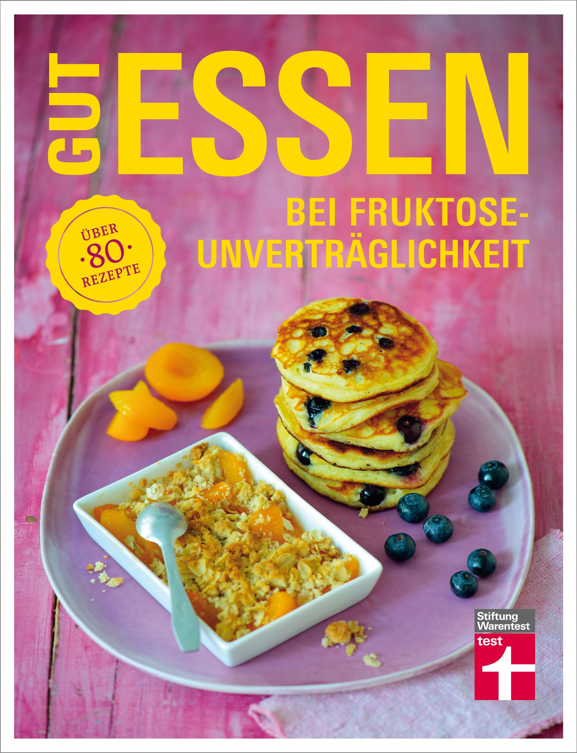 Buchcover: GUT ESSEN bei Fruktoseunverträglichkeit. Auf einem Teller: Pfannkuchen, Blaubeeren, Aprikosen und Crumble. Stiftung Warentest.