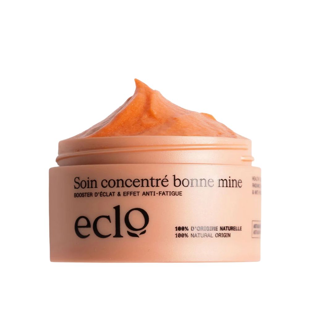 Beige Tiegel mit orangefarbenem Inhalt. Aufschrift: Soin concentré bonne mine, eclo, 100% d'origine naturelle.