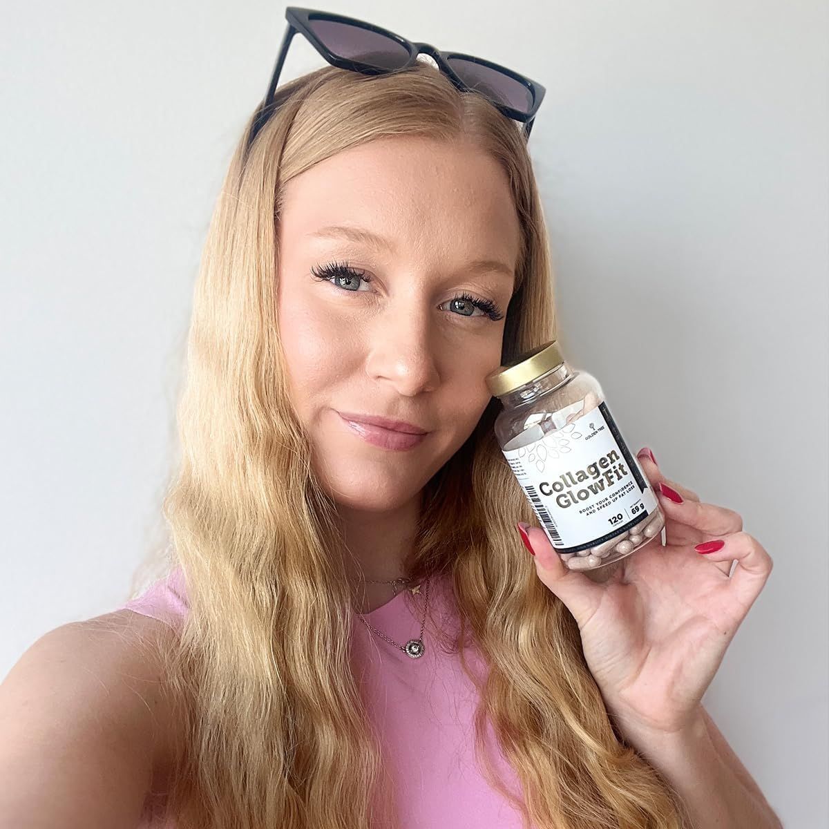 Junge Frau hält Golden Tree Collagen GlowFit Flasche. Selfie-Perspektive.
