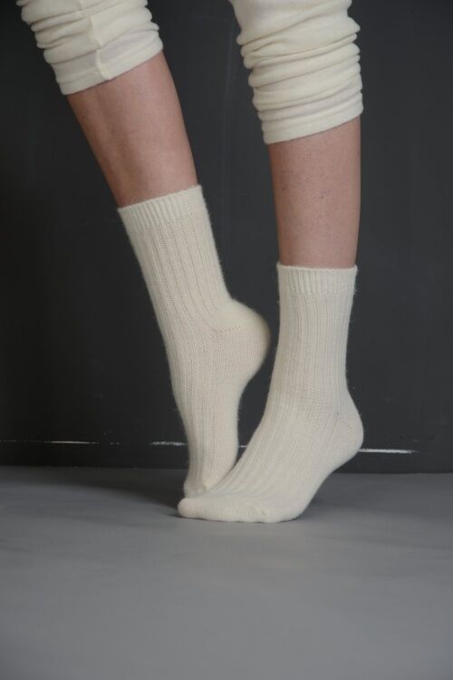 Beige Socken mit geripptem Muster. Füße und Beinbekleidung auf grauem Untergrund.