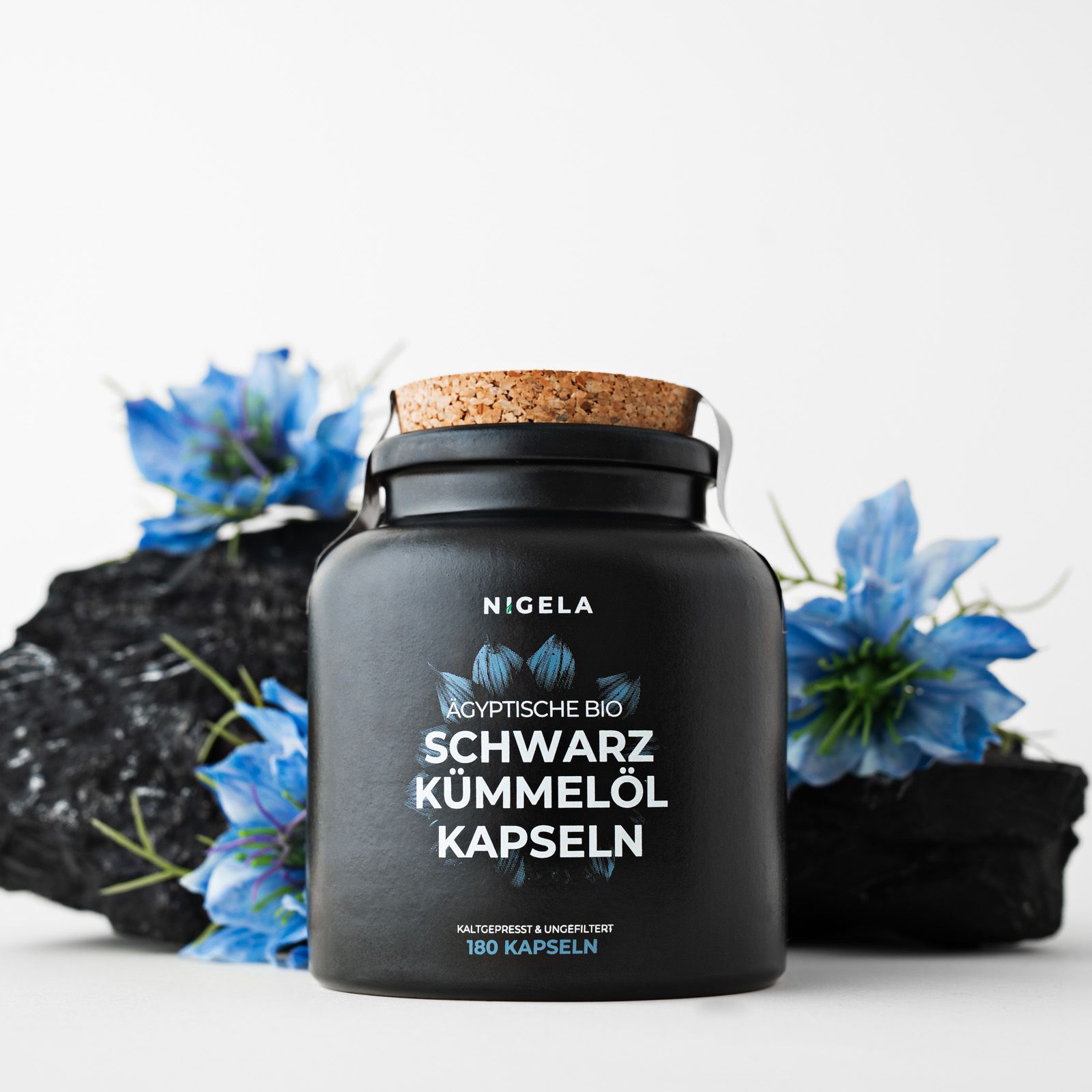 Schwarze Flasche mit Kapseln. Aufschrift: Nigela Schwarzkümmelöl Kapseln. 180 Kapseln. Mit Korken verschlossen.