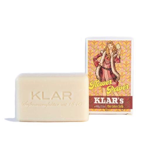 Rechteckige Seife neben Kartonverpackung. Aufdruck: Klar's, Seifenmanufaktur seit 1840. Verpackung: Flower Power, 70er Jahre Seife.