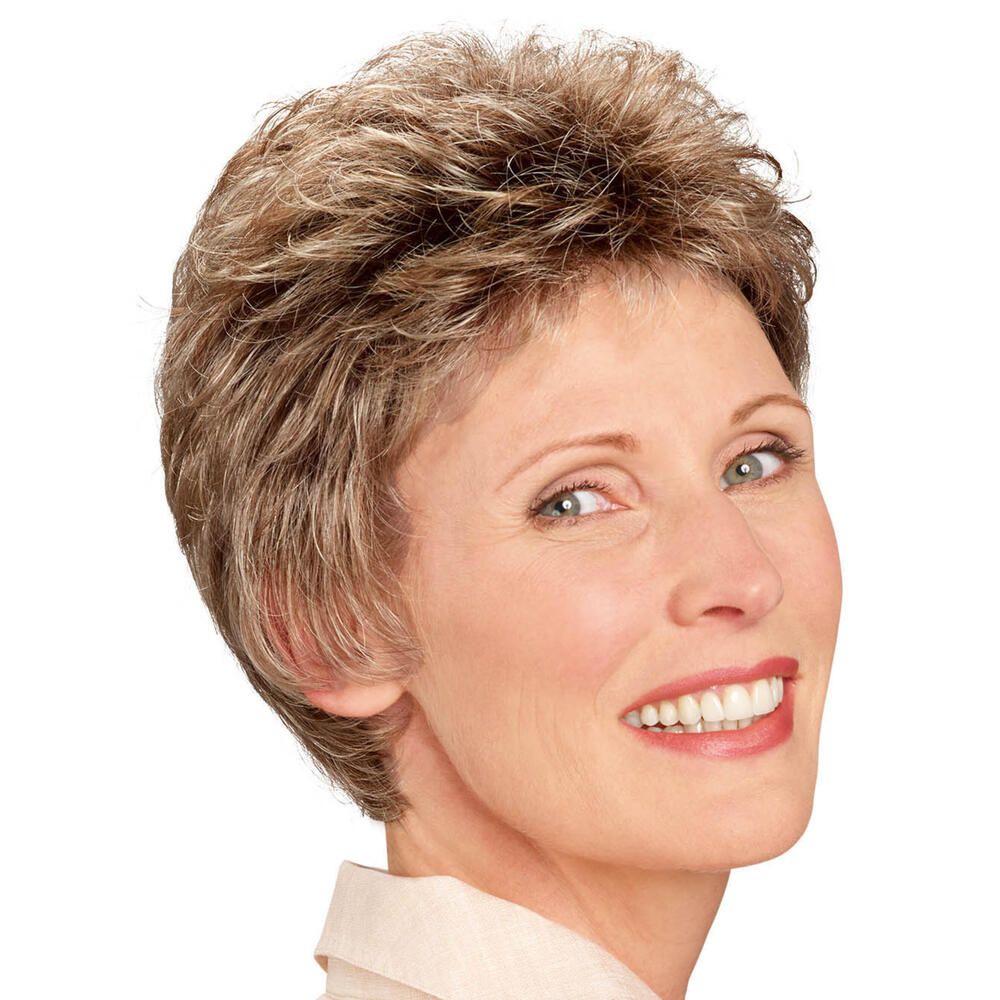 Kurzhaarperücke mit blonden Strähnen. Frau lächelt in die Kamera. Beige Bluse.