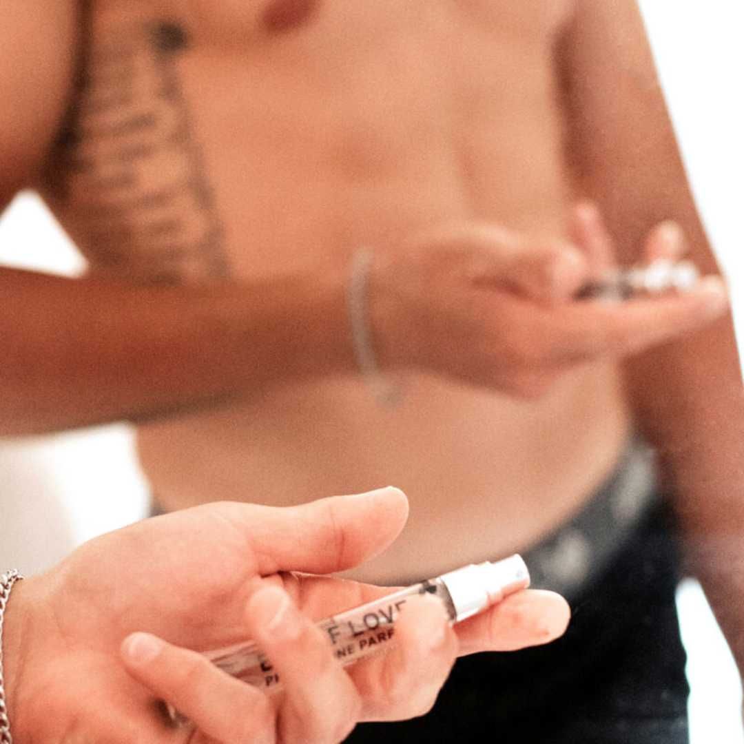 Person hält einen kleinen Sprühflakon. Auf dem Flakon steht "EYE OF LOVE" und "PHEROMONE PARFUM".