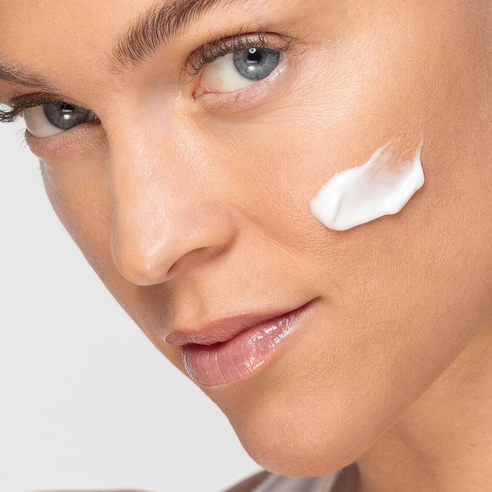 Nahaufnahme einer Frau mit Creme auf der Wange. Hautpflegeprodukt.